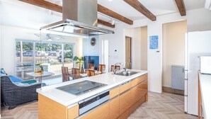 A modern kitchen with a large island, wooden beams, and a view of the outdoors. - DAIKYO ENGETSUTO VILLA　 (Shirahama)