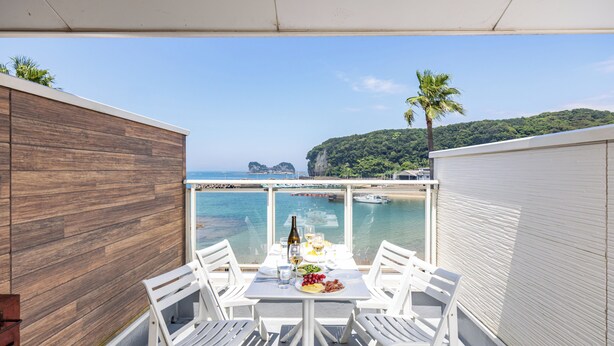 A balcony with a table set for two, overlooking a beach and the sea. - DAIKYO ENGETSUTO VILLA　 (Shirahama)