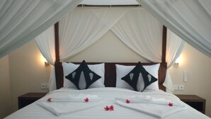 A bed with white linens, two black decorative pillows, and a canopy. - Kartika Bungalows (Ubud)