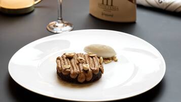 Un plato de postre con pastel de chocolate y una bola de helado, una copa de vino y una botella de vino sobre una mesa.
