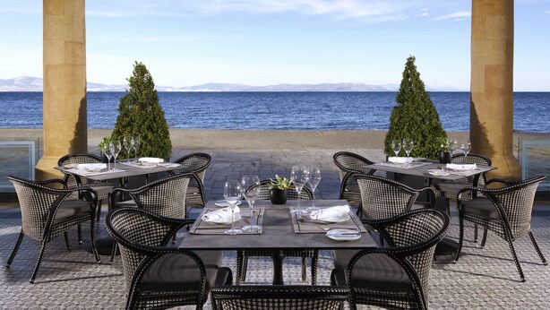 Ein Restaurant am Meer mit gedeckten Tischen und Blick auf das Wasser.