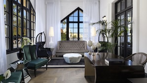 Ein geräumiges Wohnzimmer mit großem Fenster, einer Couch, einem Couchtisch und einem Schreibtisch mit Lampe.