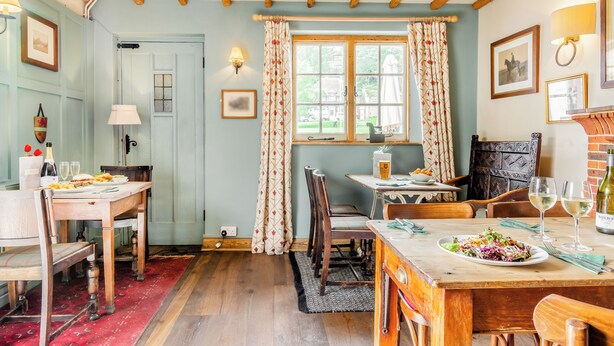 Un espace repas avec des tables et des chaises en bois, une fenêtre avec des rideaux et une porte.
