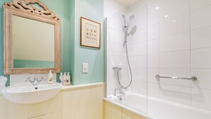 Une salle de bain avec un lavabo, un miroir, une douche et un tableau encadré au mur.