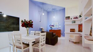 A modern living room with a dining area, a flat-screen TV, and a blue accent wall. - Opus Casa Vacanze (Pompei)