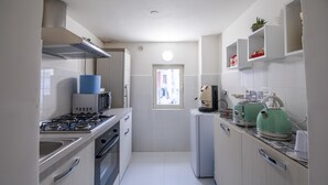 A compact kitchen with a gas stove, microwave, and a small refrigerator. - Opus Casa Vacanze (Pompei)