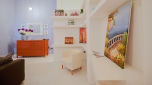 A modern living room with a sofa, a white armchair, a red dresser, and a large painting on the wall. - Opus Casa Vacanze (Pompei)