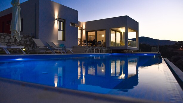 A modern house with a swimming pool, outdoor seating, and a mountain backdrop. - Sea View Villas (Malevizi)