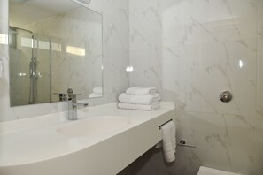 A modern bathroom with a white marble sink, a glass-enclosed shower, and a towel rack. - Sea View Villas (Malevizi)
