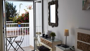 A room with a balcony, a desk, a chair, a bed, and a mirror. - Hostal Tres Soles (Nerja)