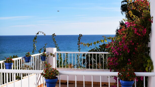 A balcony with potted plants and a view of the sea. - Hostal Tres Soles (Nerja)