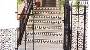 A staircase leading to a door with a decorative metal railing and a patterned tile design. - Hostal Tres Soles (Nerja)