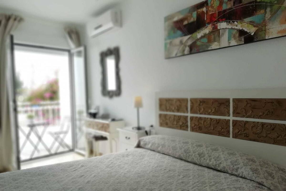 A bedroom with a bed, a dresser, a mirror, and a decorative wall panel.