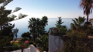 A coastal view with a clear sky, palm trees, and a body of water. - Hostal Tres Soles (Nerja)