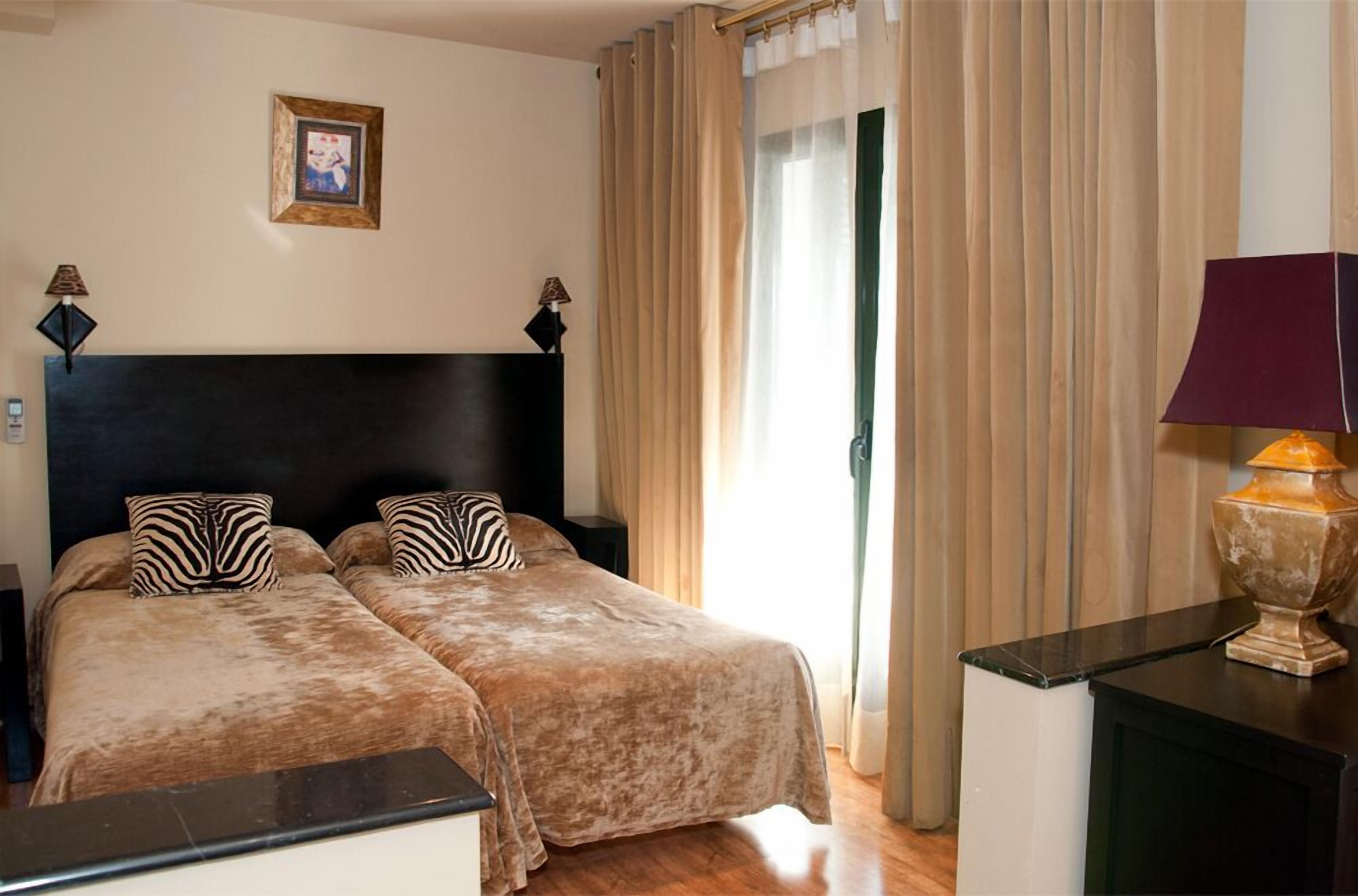 A double bed with zebra-patterned pillows, a dark headboard, and a bedside table with a lamp.