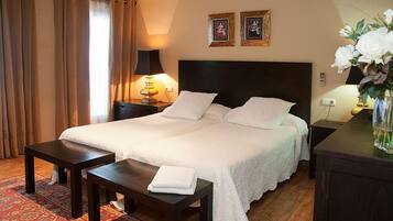 Ein Hotelzimmer mit einem großen Bett, zwei Nachttischen, einer Lampe und einer Vase mit Blumen.