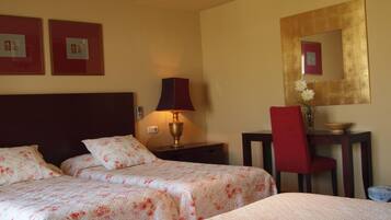 A hotel room with two beds, a desk, a chair, a lamp, and a mirror.