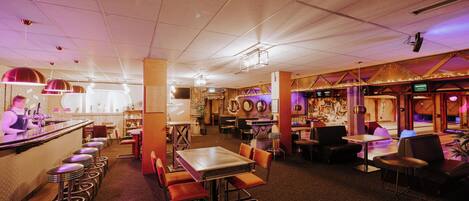 A restaurant interior with a bar area, seating arrangements, and a stage for performances.