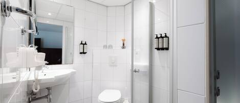 A modern bathroom with a white sink, toilet, and shower.
