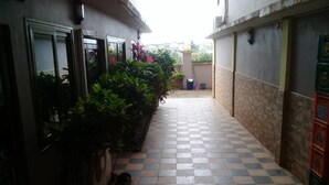 Un corridoio stretto con pavimento a scacchi, fiancheggiato da piante e un edificio dalla facciata piastrellata.