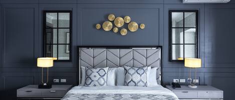 A modern hotel room with a large bed, two bedside tables, and a wall-mounted air conditioner.