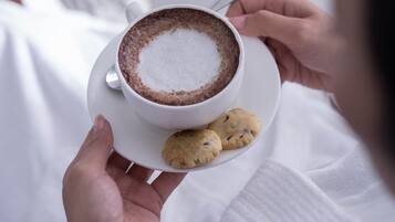 Une personne tenant une tasse de café avec une soucoupe et deux biscuits.