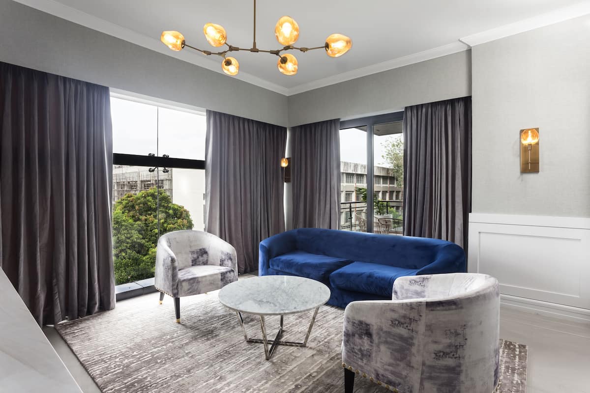 Una sala de estar moderna con un sofá azul, dos sillones, una mesa de centro de mármol y una araña.