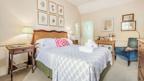 Un dormitorio ordenado con cama, mesitas de noche, una silla y cómoda.
