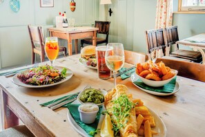 A dining table with a variety of dishes including fish and chips, a burger, and a salad. - Grace - Tiger Inn (Eastbourne)