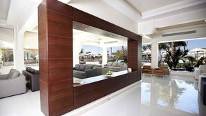 A modern living area with a large wooden partition, a pool, and outdoor seating visible through large windows. - Mousa Coast (Ras Sudr)