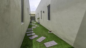 A narrow corridor with artificial grass and stepping stones, flanked by plain walls and small windows. - Hotel Seri Rembau (Rembau)