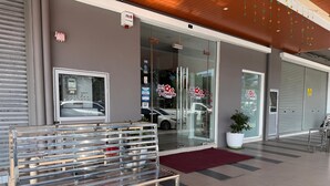 A modern hotel entrance with a glass door, a bench outside, and a red carpet leading to the entrance. - Hotel Seri Rembau (Rembau)