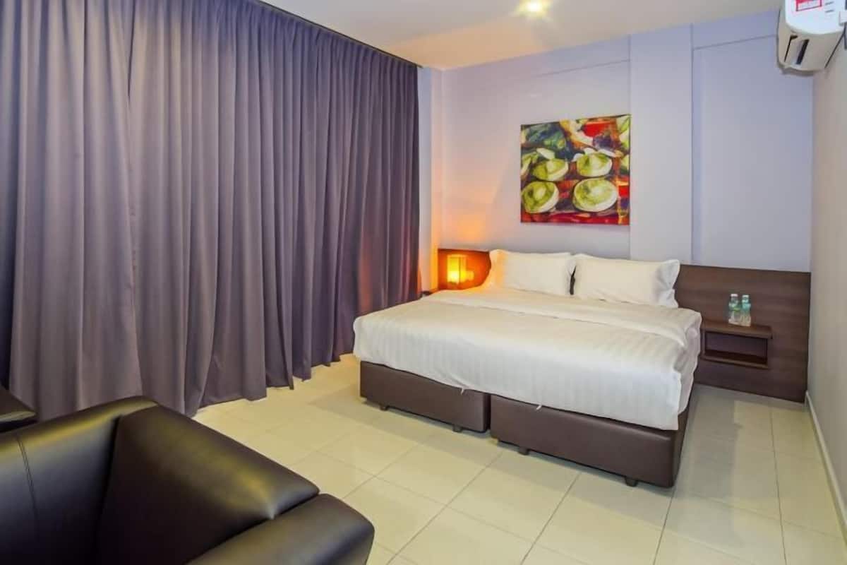 A hotel room with a bed, a nightstand, a lamp, a painting on the wall, and a curtain.
