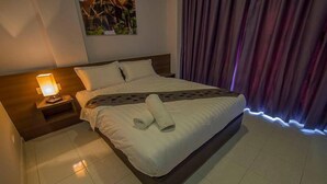 A neatly made bed with a rolled towel, a nightstand with a lamp, and a painting on the wall. - Hotel Seri Rembau (Rembau)