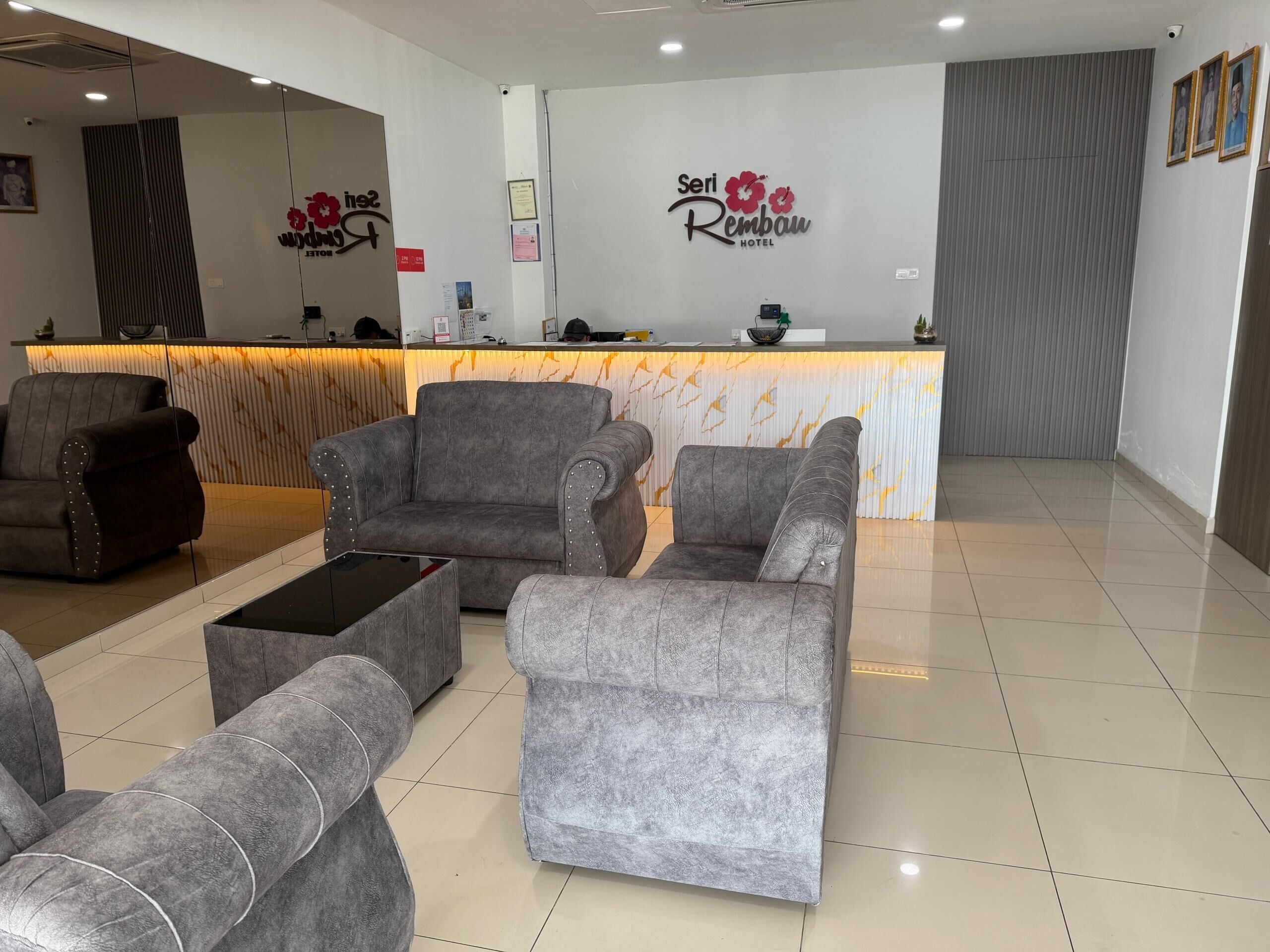 A hotel reception area with a marble counter, grey upholstered seating, and framed pictures on the wall.
