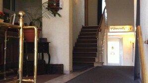 Eine Treppe führt zu einer zweiten Etage, über der Tür hängt ein Schild mit der Aufschrift 'Gästehaus'.