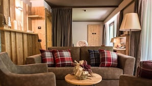 Una sala de estar acogedora con un conjunto de sofás, una mesita redonda con un centro decorativo y una lámpara sobre una mesita auxiliar.