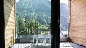 Un balcón de madera con vistas a una montaña boscosa.