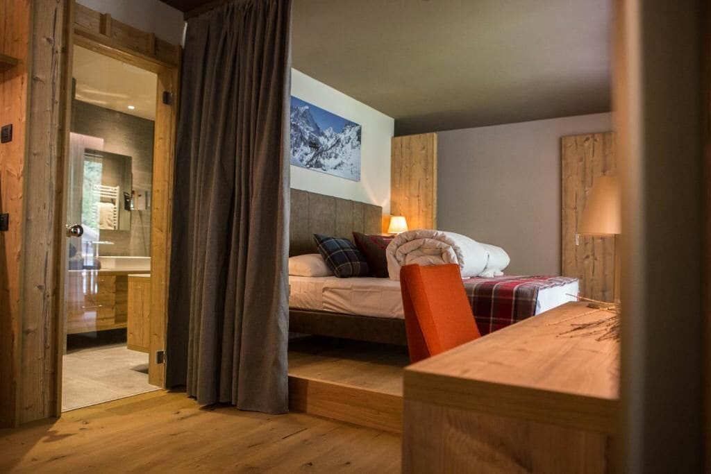 Une chambre confortable avec un lit, un bureau en bois et une vue sur une montagne enneigée.