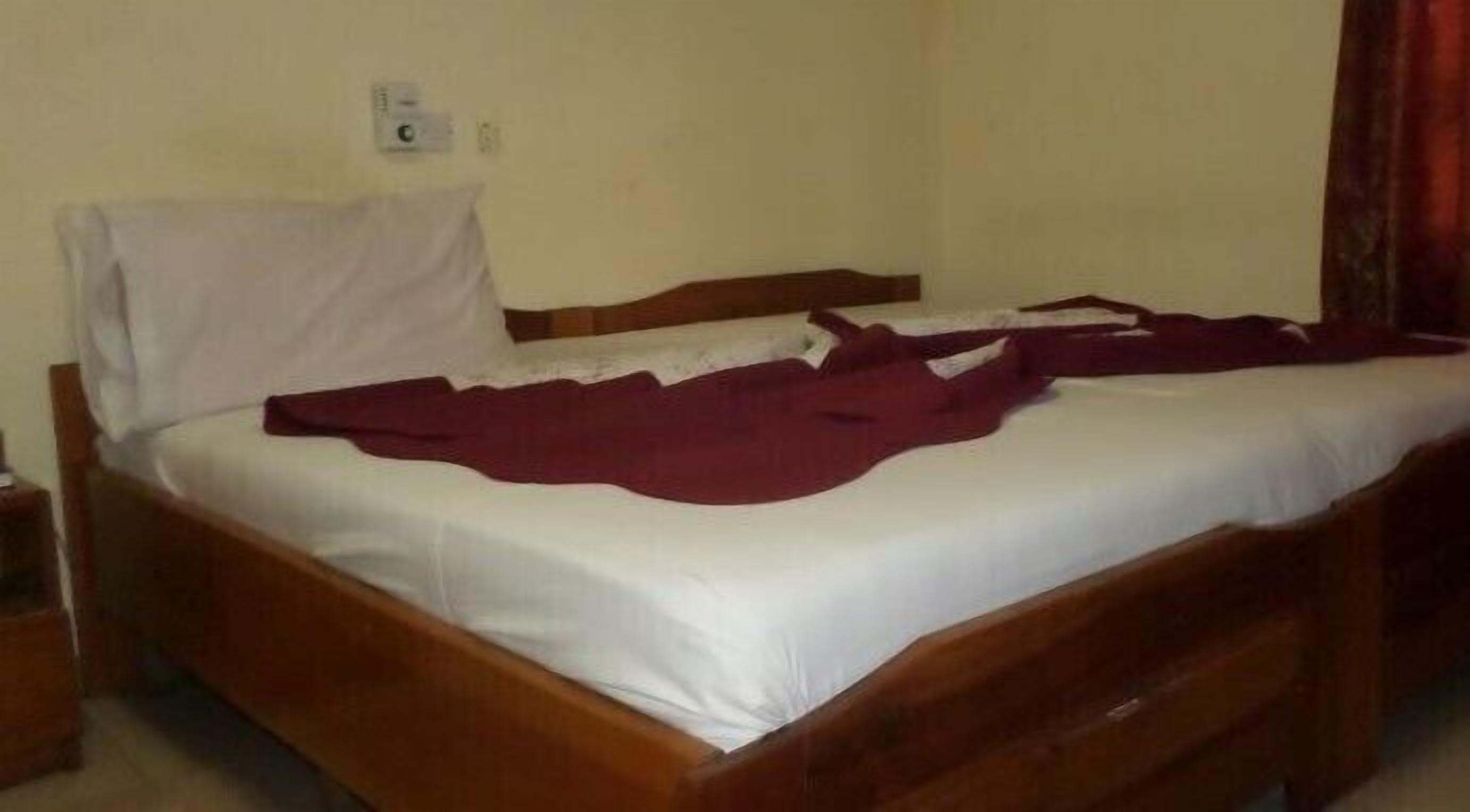 Una cama individual con estructura de madera y ropa de cama blanca.