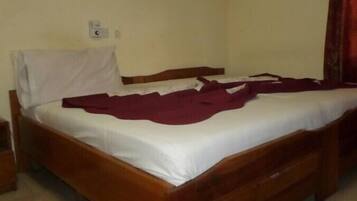 Una cama individual con estructura de madera y ropa de cama blanca.