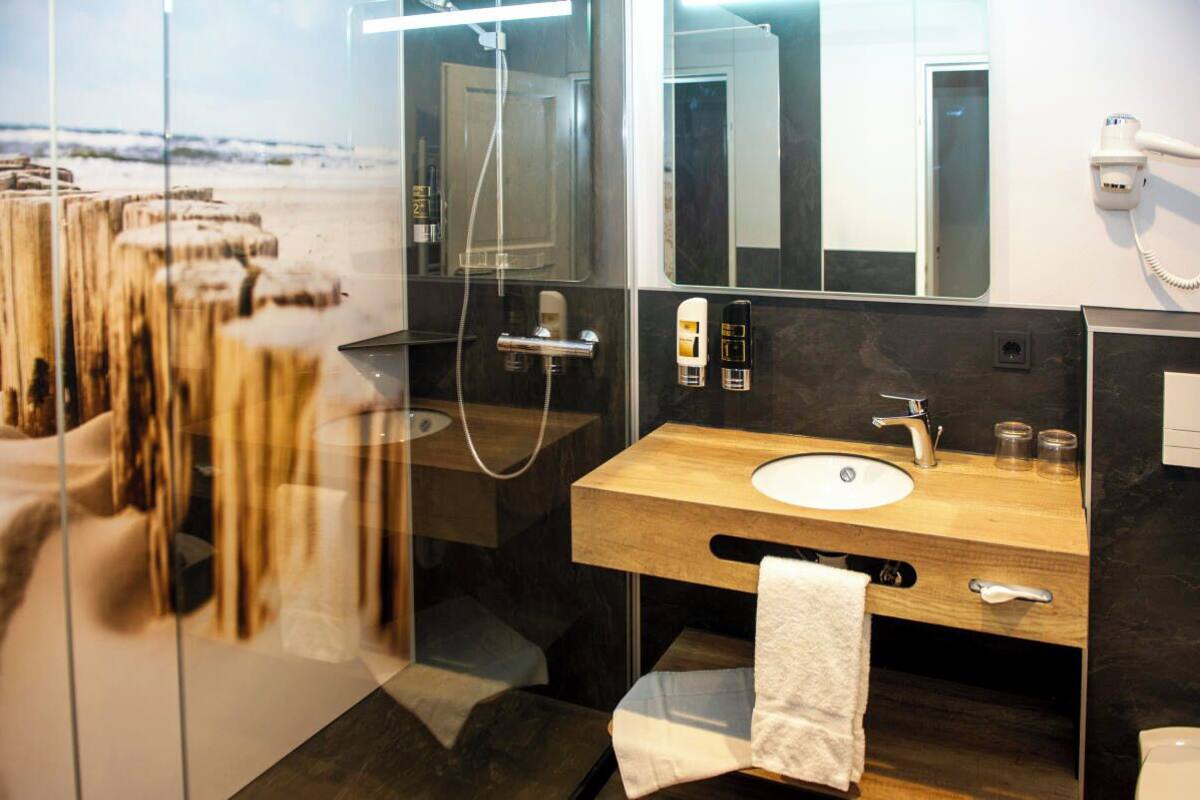 A modern bathroom with a wooden vanity, a large mirror, and a glass shower enclosure.