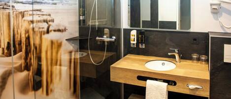 Ein modernes Badezimmer mit einem Holzwaschtisch, einem großen Spiegel und einer Duschkabine aus Glas.