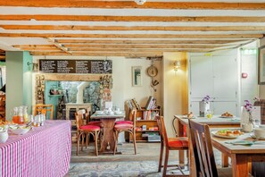 A cozy dining area with wooden beams, a chalkboard menu, and a variety of seating options. - Patience - Tiger Inn (Eastbourne)