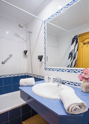 A bathroom with a white sink, blue countertop, and a shower with a handheld showerhead.