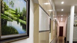 A corridor with a framed landscape painting, marble flooring, and a door at the end. - Hotel Hai Au (Hanoi)
