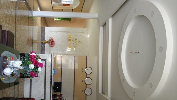 A hotel reception area with a marble floor, a reception desk, a clock, and a wall-mounted circular window. - Hotel Hai Au (Hanoi)