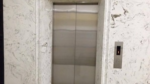 An elevator with a marble wall and floor, featuring a simple design with a control panel on the right. - Hotel Hai Au (Hanoi)