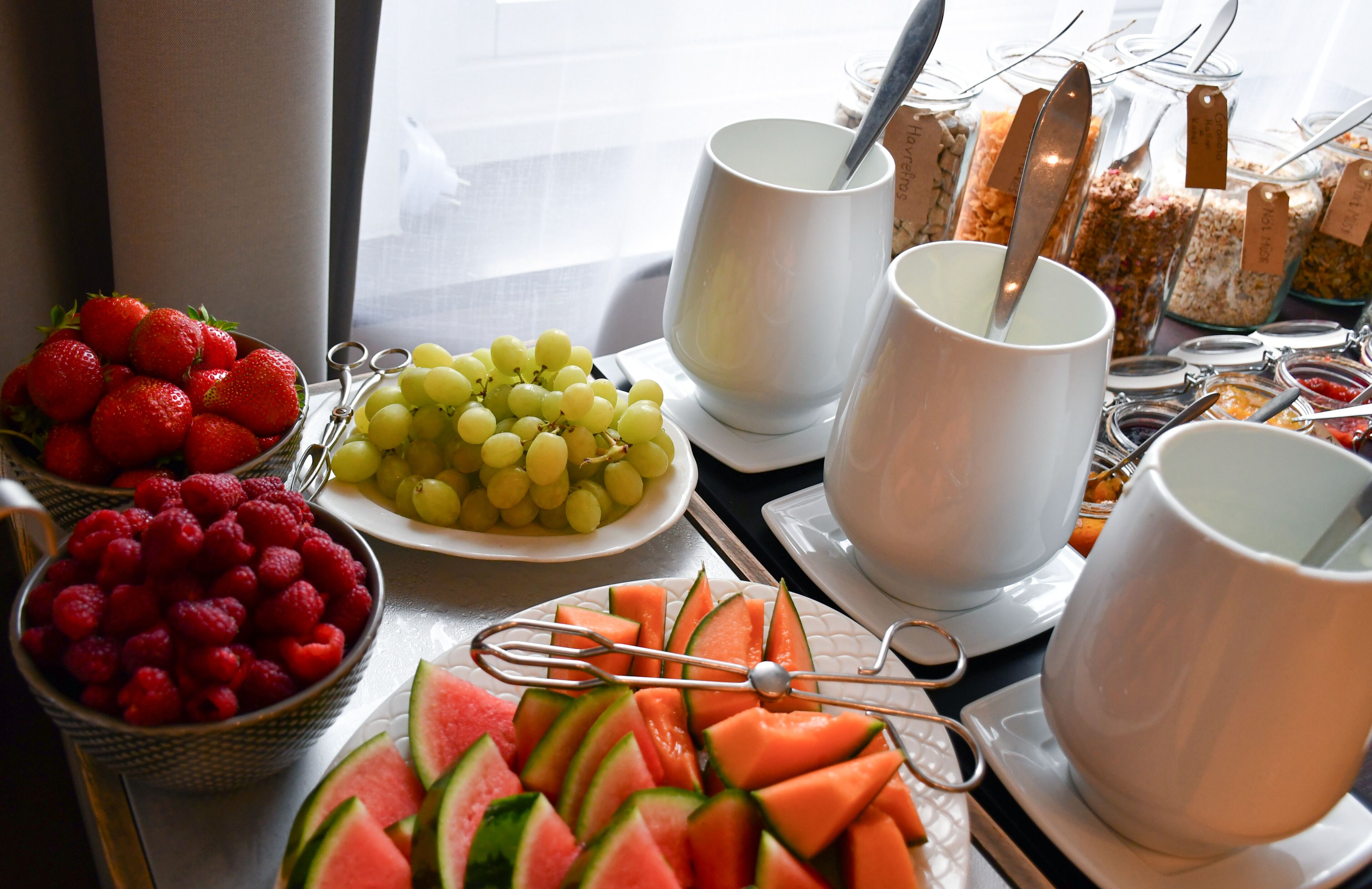 Een ontbijtbuffet met verschillende soorten fruit, yoghurt en ontbijtgranen.