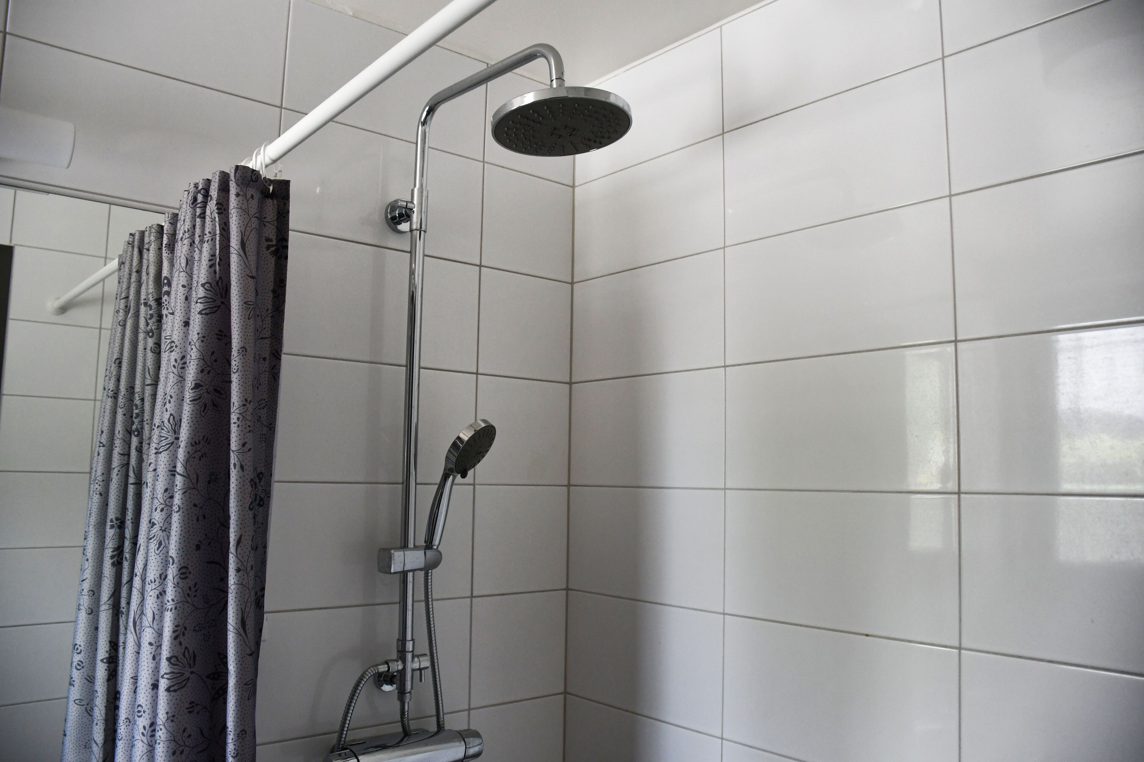 A shower area with a modern design, featuring a rain showerhead and a handheld shower attachment.